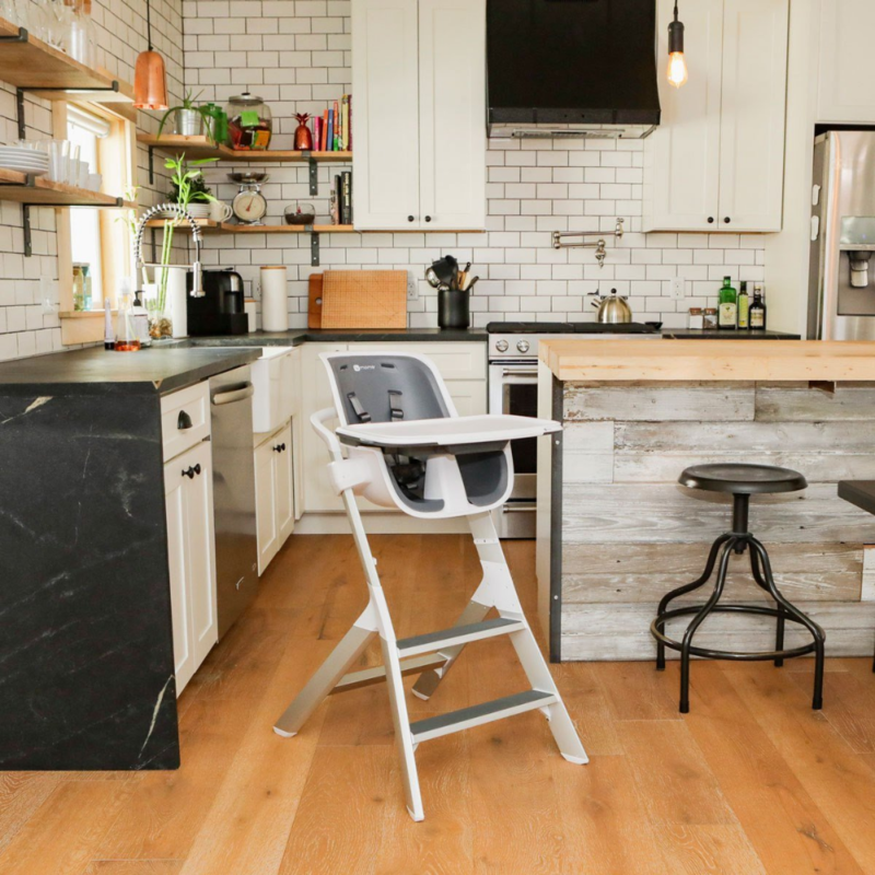Baltos spalvos 4MOMS Connect maitinimo kėdutė stovinti virtuvėje