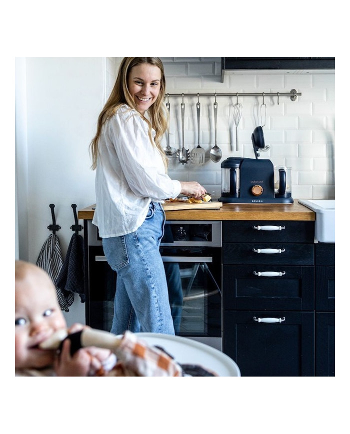 Mama virtuvėje ruošia maistą šalia BEABA Babycook Plus garintuvo trintuvo