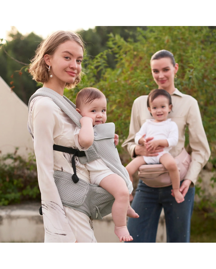 Mama lauke neša kūdikį pilkoje Momcozy Move2Fit nešioklėje